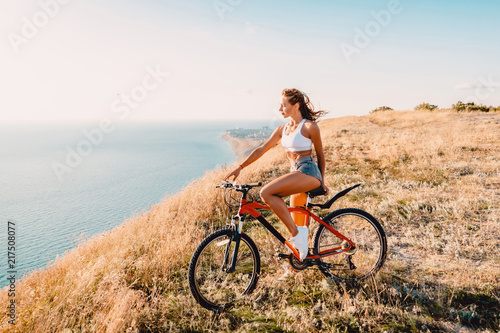 Young pretty woman with mountain bicycle in white shirt, shorts and white sneakers