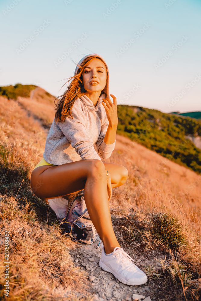 Woman relaxing in nature at warm sunset. Attractive girl in the mountains