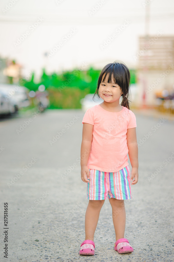 portrait of happy little girl standing on the road