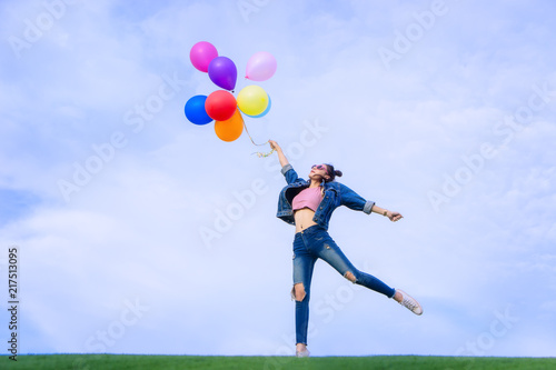 The jumping girl holds a ball of light color on a bright sky background