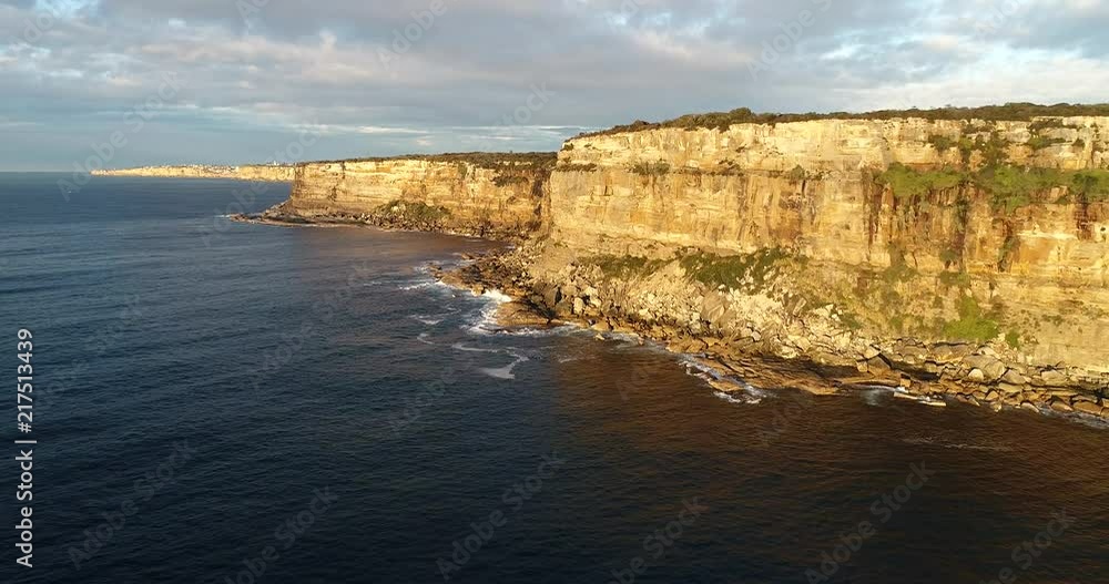 Above sea level flying up to eroded steep cliffs of North Head towards distant Sydney city CBD skyline around Sydney harbour.
Above sea level flying up to eroded steep cliffs of North Head towards distant Sydney city CBD skyline around Sydney harbour.