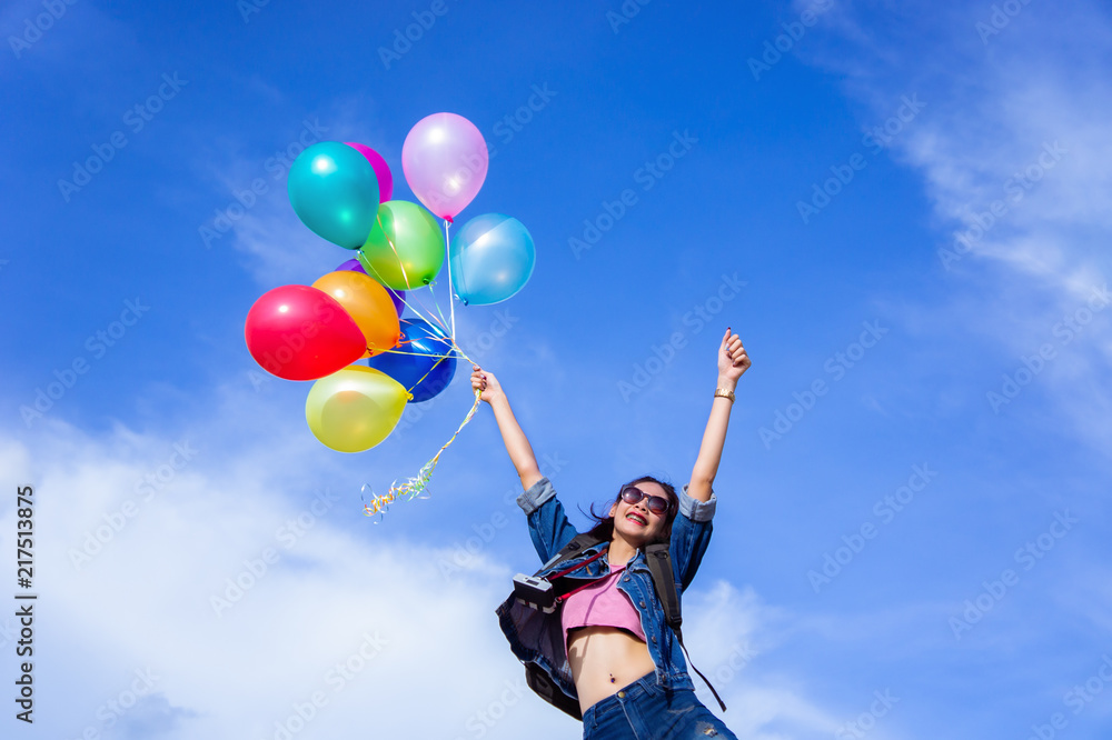 The jumping girl holds a ball of light color on a bright sky background The jumping girl holds a ball of light color on a bright sky background