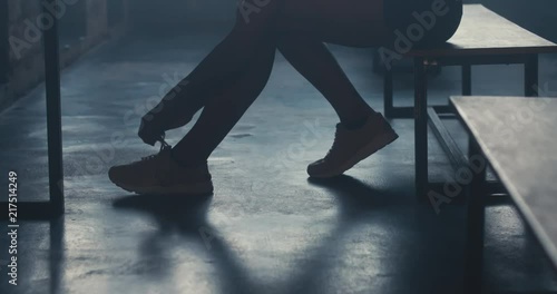 CU DOLLY IN Caucasian female athlete preparing for a workout in a gym locker room, tying shoelaces before training session. 4K UHD 60 FPS SLOW MOTION