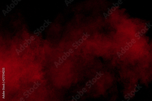 abstract red dust splattered on black background. Red powder explosion.Freeze motion of red particles splashing.