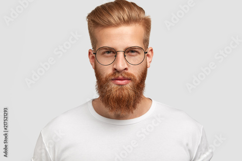 Fotografia Headshot of attractive serious Caucasian male with thick ginger beard and trendy
