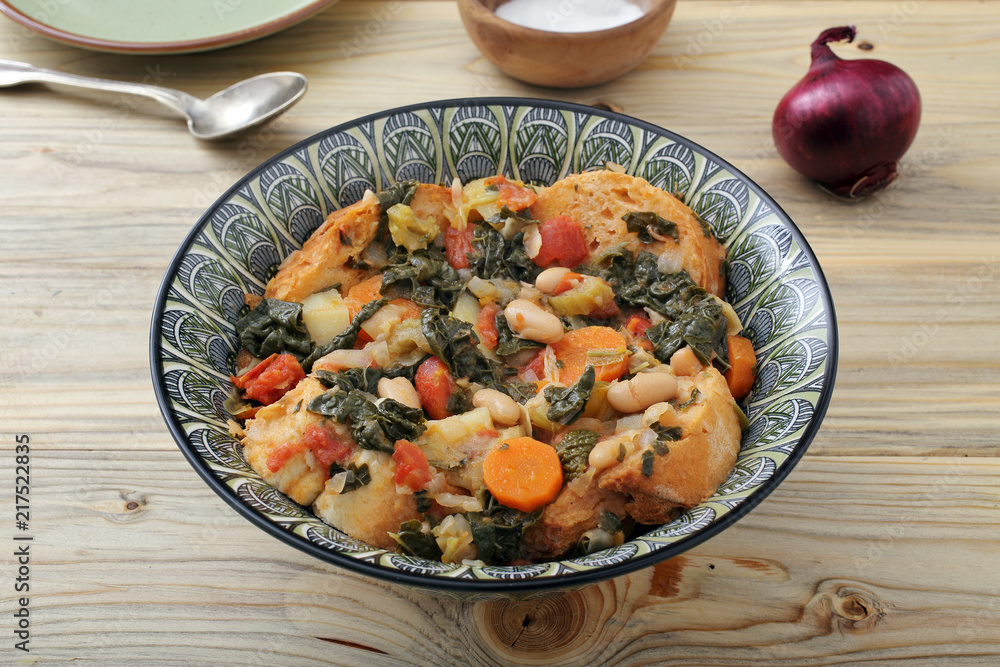 Naklejka premium zuppa o minestra di pane con verdure su tavolo di legno