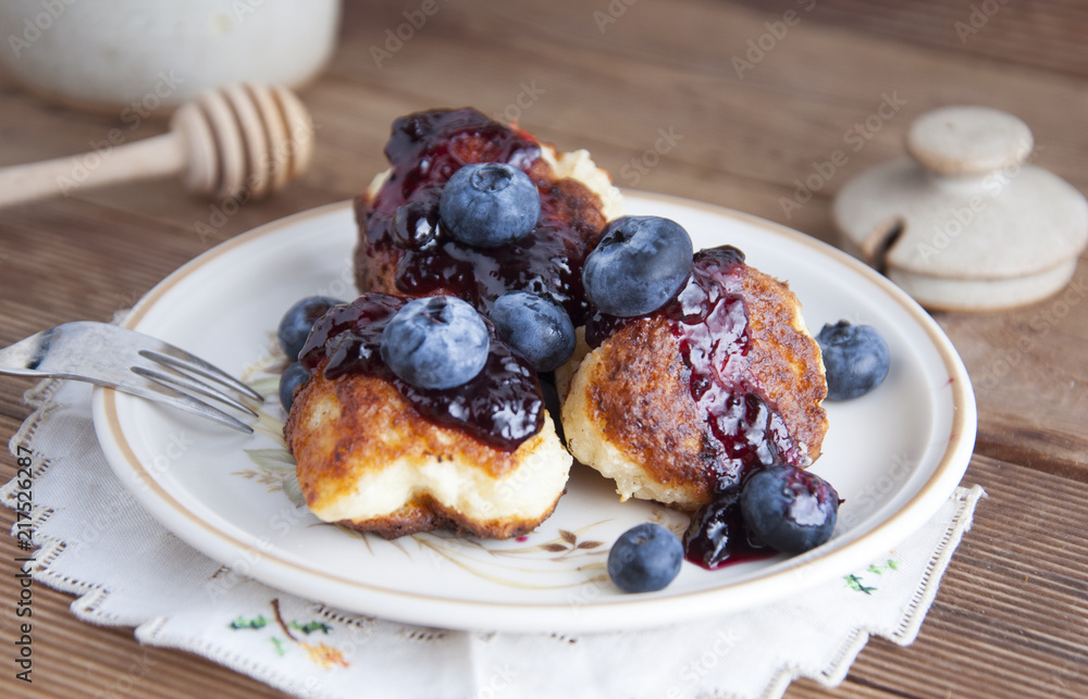 Homemade cheese donuts with berry jam and blueberry. Healthy breakfast or snack, round plate, rustic wooden background. Homemade cheese donuts with berry jam and blueberry. Healthy breakfast or snack, round plate, rustic wooden background.