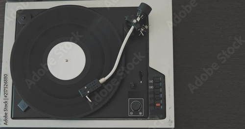 The man's hand puts the needle on the vinyl record and starts the player. photo