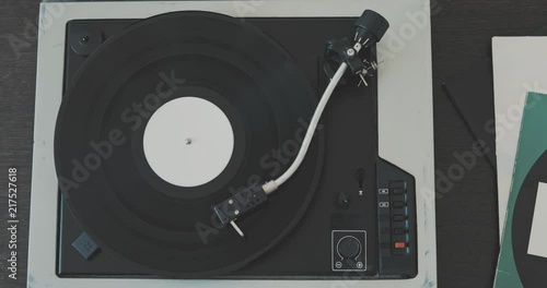 The man's hand puts the needle on the vinyl record and starts the player. photo