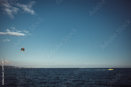 Parachute over the sea against a blue sky and clear sea water, towing on a boat. Riding a parachute behind a boat. The concept of travel, release, summer, rest