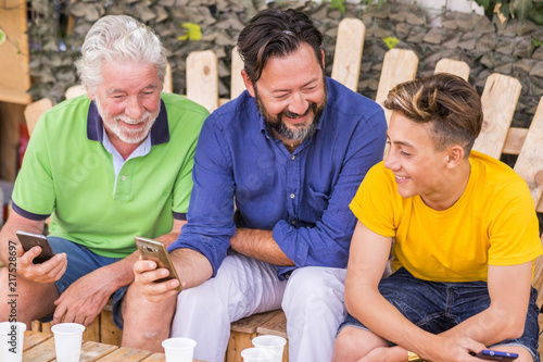 Bild auf Leinwand family generations men with grandfather father and son nephew from old to young stay together using cellular technology smartphone to connect to internet and check modern related concepts