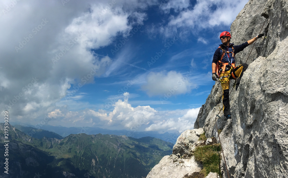 Young man climbing on a rock in Swiss Alps - via ferrata/klettersteig - obrazy, fototapety, plakaty 
