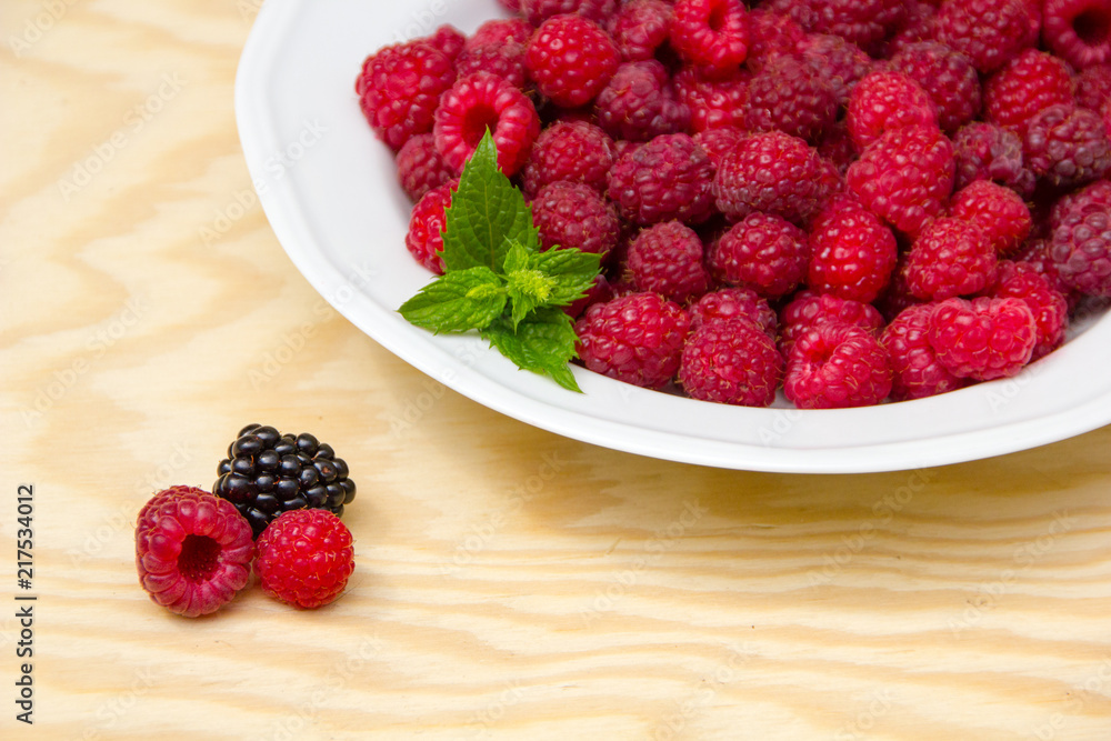 Red and delicious raspberries with mint in a white bowl Red and delicious raspberries with mint in a white bowl