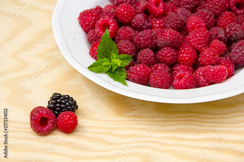Red and delicious raspberries with mint in a white bowl