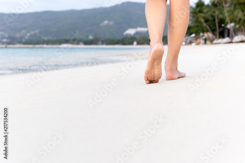 Woman walking on sand beach in tropical island.