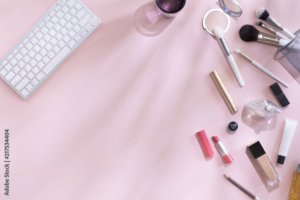 Top view of woman beauty blogger working desk with computer or laptop, notebook, decorative cosmetic, leaves shadows and hard light, envelope on pink and white pastel table. Flat lay background. Top view of woman beauty blogger working desk with computer or laptop, notebook, decorative cosmetic, leaves shadows and hard light, envelope on pink and white pastel table. Flat lay background.