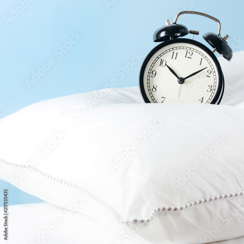 Alarm clock on the pillows. Advertising concept, copy space