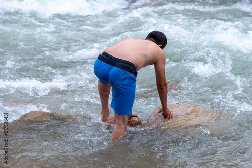 a man is bathing on a mountain river