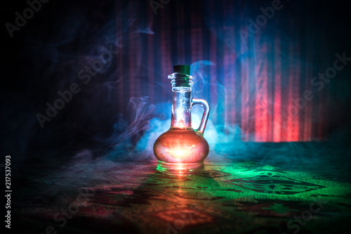 Antique and vintage glass bottles on dark foggy background with light. Poison or magic liquid concept.