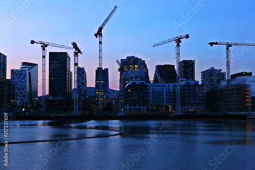 Background of silhouette skyscrapers and cranes under construction. Industrial city landscape at night, Bjorvika, Oslo, Norway. photo