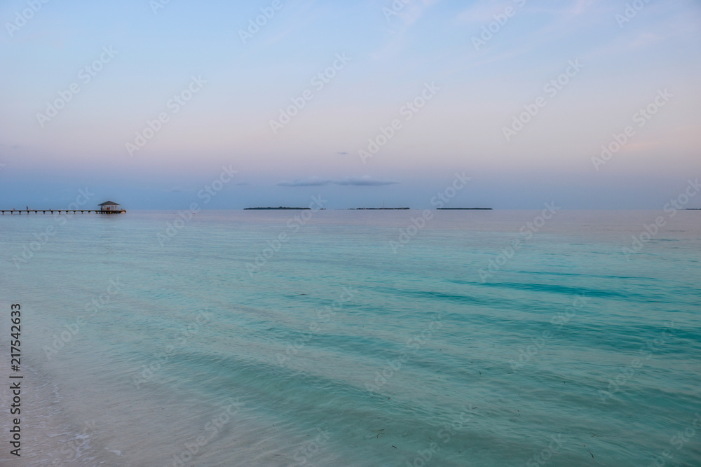 Dieses bild zeigt den türkisen ozean auf den malediven bei total ruhigem meer am frühen morgen. im hintergrund ist der bootsteeg zu sehen. Das bild wurde im süd male atoll aufgenommen Dieses bild zeigt den türkisen ozean auf den malediven bei total ruhigem meer am frühen morgen. im hintergrund ist der bootsteeg zu sehen. Das bild wurde im süd male atoll aufgenommen