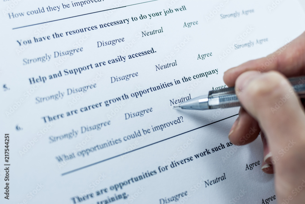 Respondent holding a pan in a hand and answeing questions in employee survey. Questions relating to managerial practices, corporate culture, career growth, and professional relationships. Close-up Respondent holding a pan in a hand and answeing questions in employee survey. Questions relating to managerial practices, corporate culture, career growth, and professional relationships. Close-up