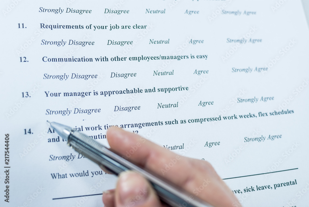 Respondent holding a pan in a hand and answeing questions in employee survey. Questions relating to managerial practices, corporate culture, career growth, and professional relationships. Close-up Respondent holding a pan in a hand and answeing questions in employee survey. Questions relating to managerial practices, corporate culture, career growth, and professional relationships. Close-up