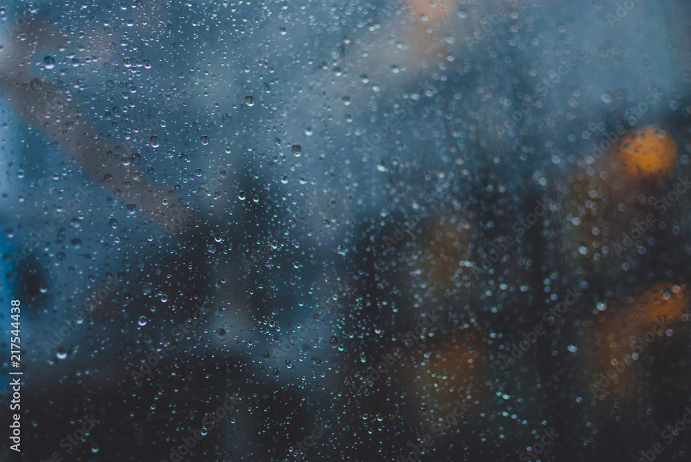 Obraz premium Closeup of raindrops on window glass. Blurred office lights on background. Evening