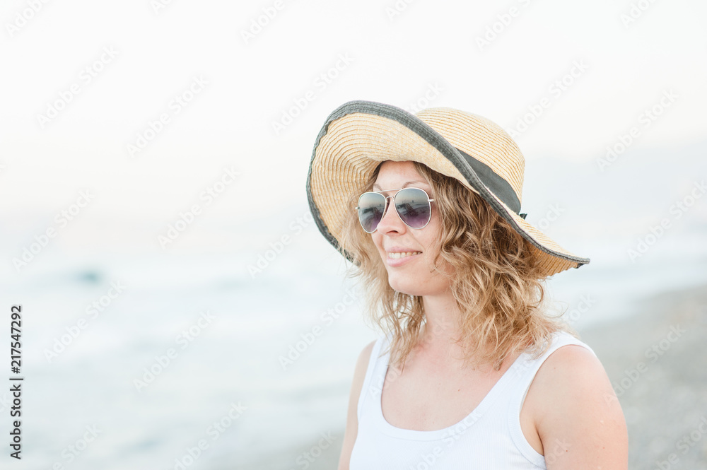 Portrait of happy smiling young woman with long hair on the beach and sea background