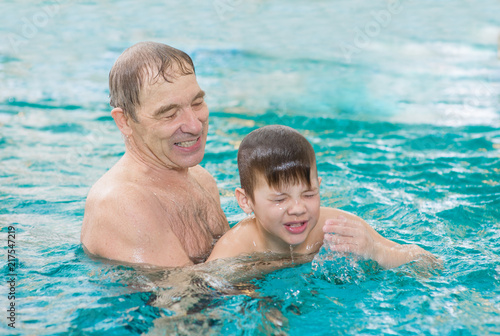 Happy senior man teaches to swim a boy in the pool © Ermolaev Alexandr