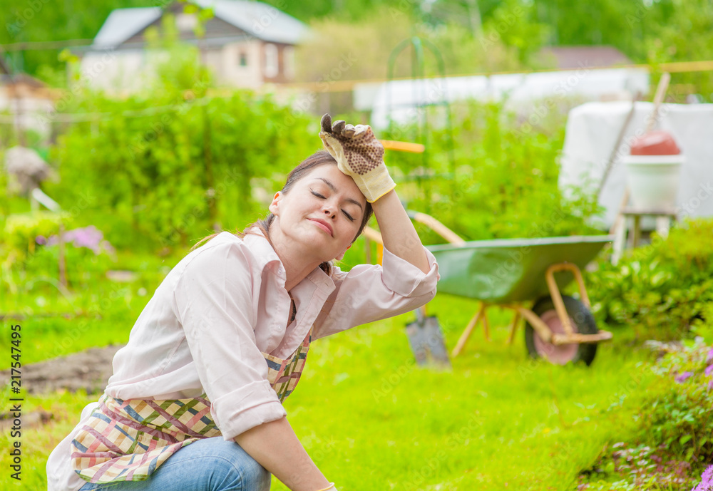 Tired woman planting flowers at back yard Tired woman planting flowers at back yard