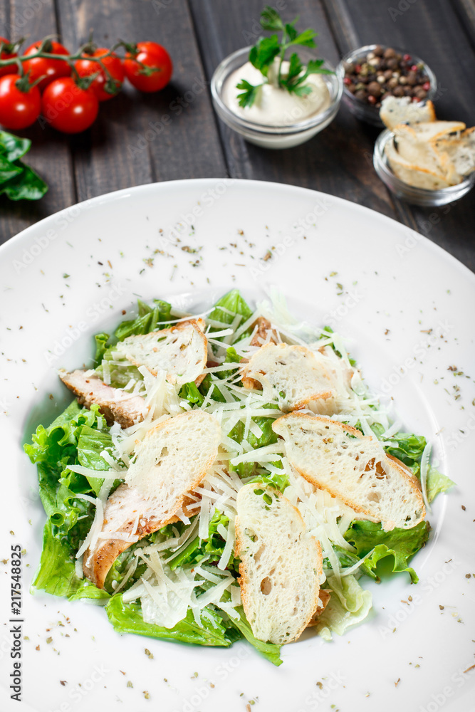 Salad with chicken breast, parmesan cheese, croutons, mixed greens, lettuce on wooden background. Healthy food.