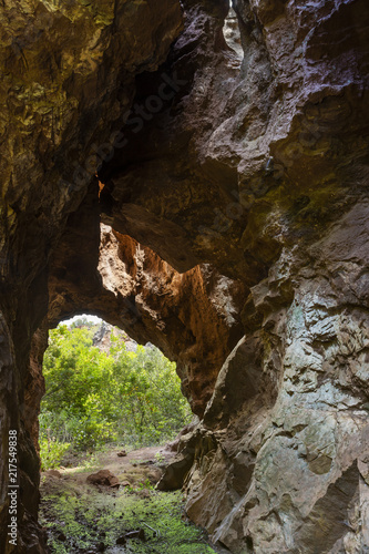 View to small tunnel in big hard rock leading to green forest in Cerro del Hierro, Seviile