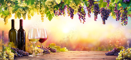 Fotografia, Obraz Bottles And Wineglasses With Grapes At Sunset