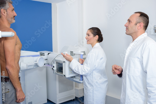 doctors taking upright x-ray of mans abdomen