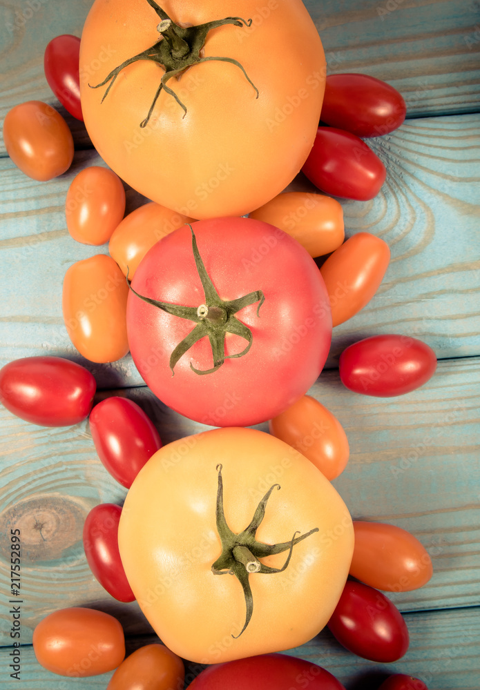 Different varieties of tomatoes on a blue wooden background. Different varieties of tomatoes on a blue wooden background.