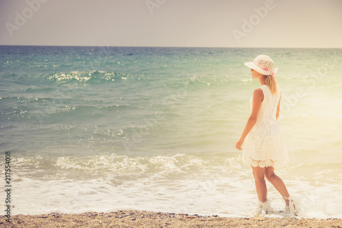 Lonely young woman walking on the sunset beach