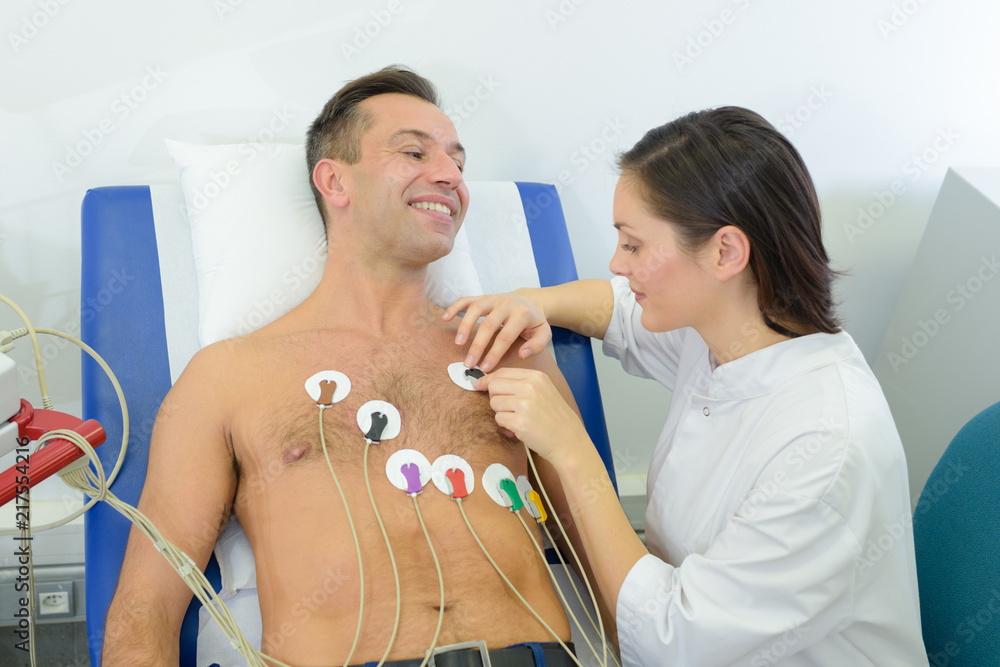 Nurse attaching heart monitor pads to patient - obrazy, fototapety, plakaty 