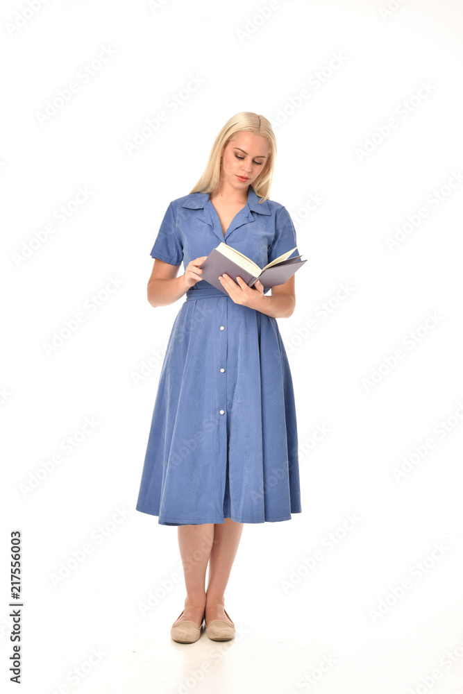 full length portrait of blonde girl wearing blue dress. standing pose holding a book. isolated on white studio background. full length portrait of blonde girl wearing blue dress. standing pose holding a book. isolated on white studio background.