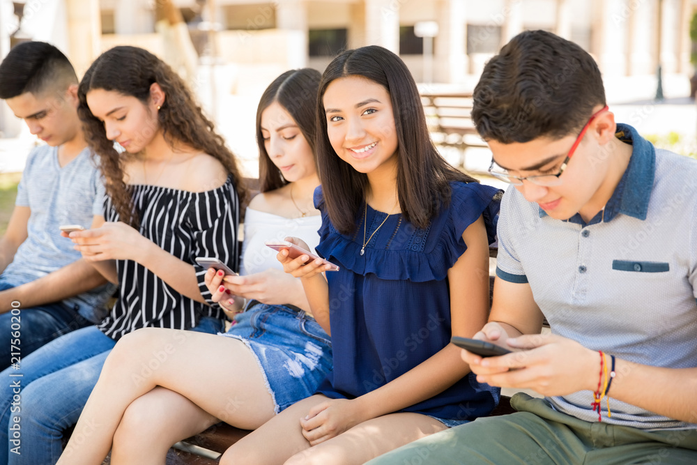 Teenage girl with friends using phones Teenage girl with friends using phones