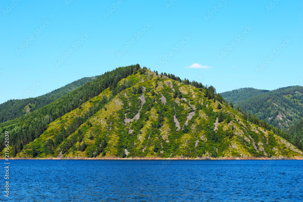Picturesque view of the rocks surrounded by the sea.  Rocky shore. High mountains against the sky. Sea cruise. Huge space. Wildlife. Beautiful Siberian nature.