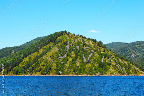 Picturesque view of the rocks surrounded by the sea. Rocky shore. High mountains against the sky. Sea cruise. Huge space. Wildlife. Beautiful Siberian nature.