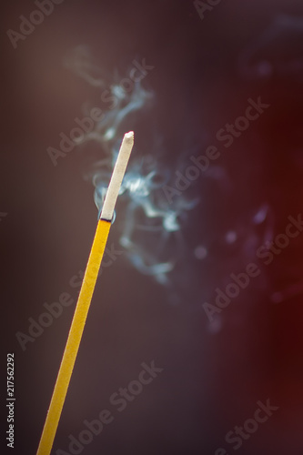 Burning incense sticks with smoke over dark background