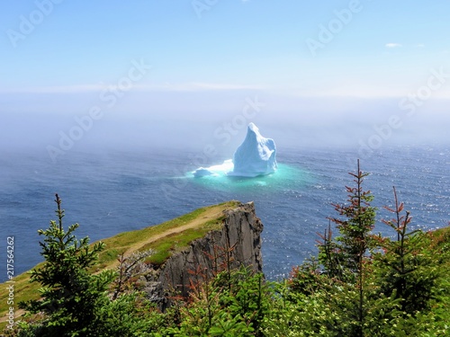 Incredible iceberg floating along the rugged coast beside the Skerwink Trail in Newfoundland and Labrador, Canada photo
