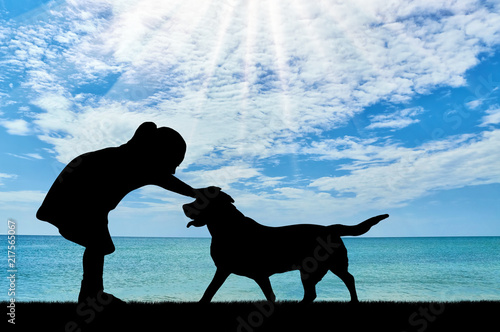 Silhouette of a baby girl stroking a dog against the sea