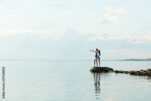 Young couple standing on pier and looking at the lake