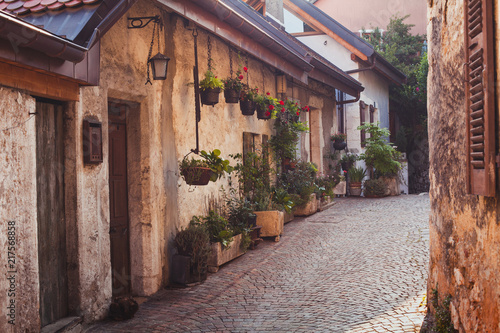 Fototapeta podróż do Europy, przytulna ulica dla pieszych ze starym chodnikiem, domy ozdobione wieloma doniczkami, Annecy, Francja