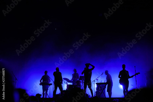 Carta da parati music band playing on concert stage, silhouettes of musicians unrecognizable, gr