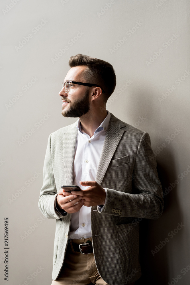 Bearded business executive holding smartphone isolated on grey background Bearded business executive holding smartphone isolated on grey background