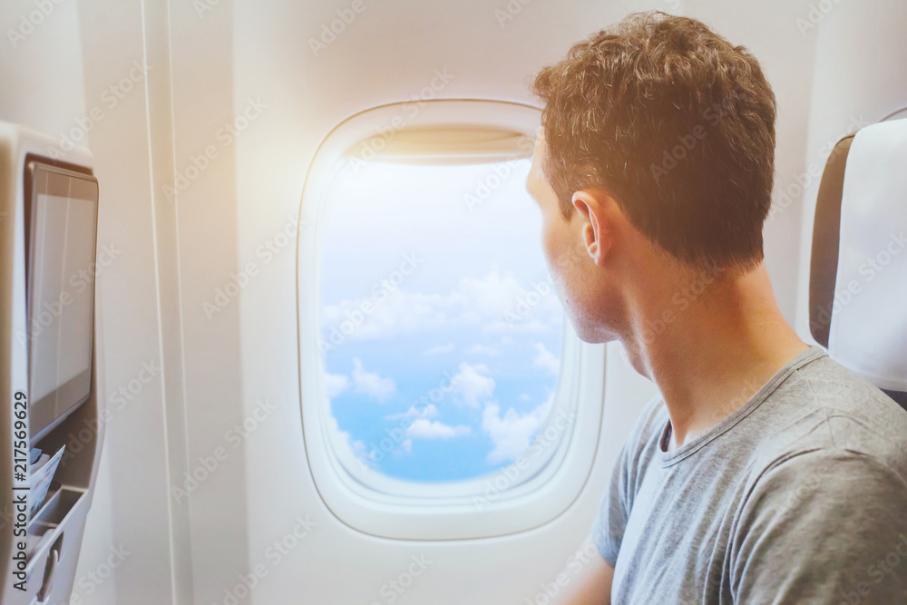 Naklejka premium passenger of airplane looking at window, international travel, happy man tourist enjoy flight in comfortable air plane